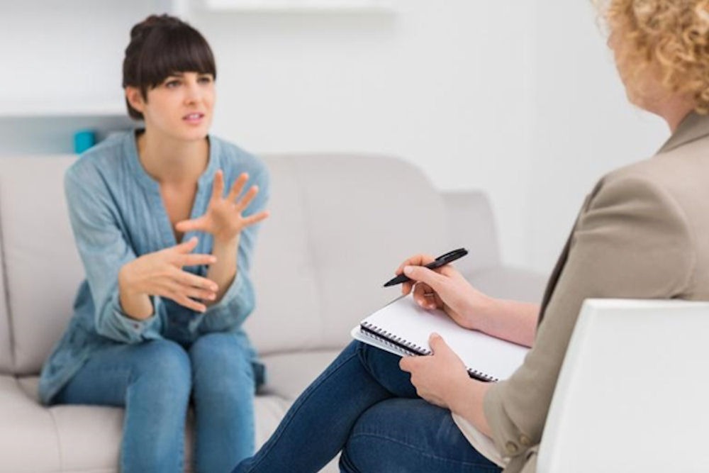 woman sitting on couch talking to a therapist