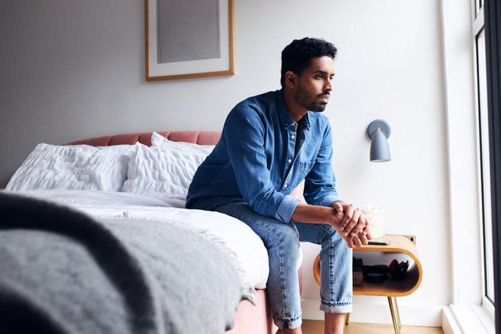 man sitting on bed considering how drugs and aging relate